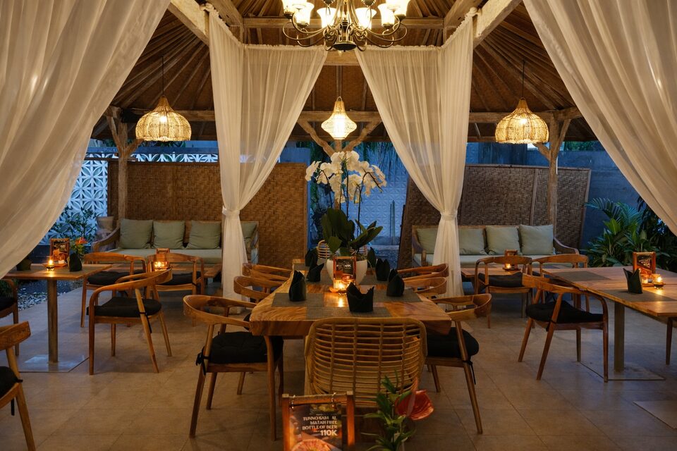 The garden pavilion at dusk, laid with black napkins and white orchids under glowing rattan lanterns.